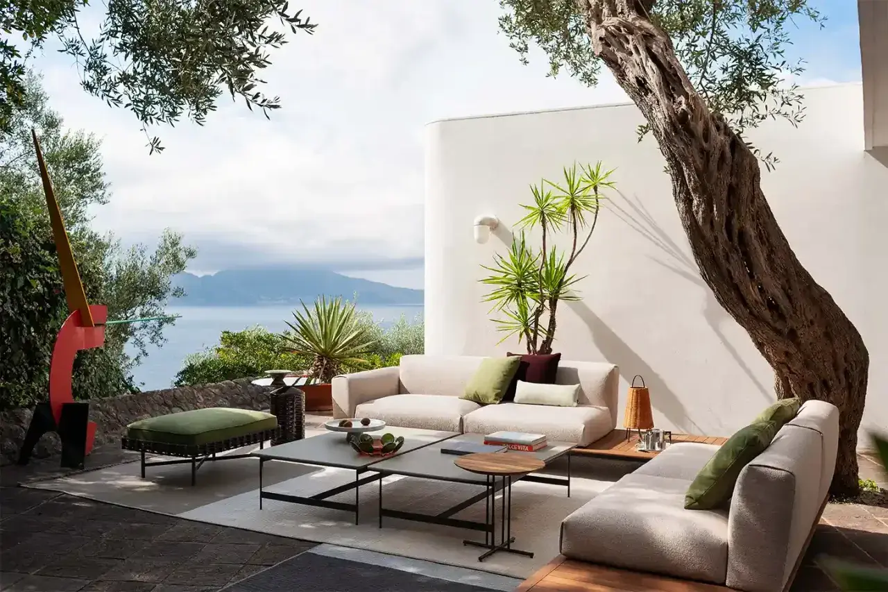 Arredamento moderno su un terrazzo scoperto con vista mare. Divani, tavolini e pouf creano un'oasi di relax, un'idea per come coprire un terrazzo scoperto con stile.
