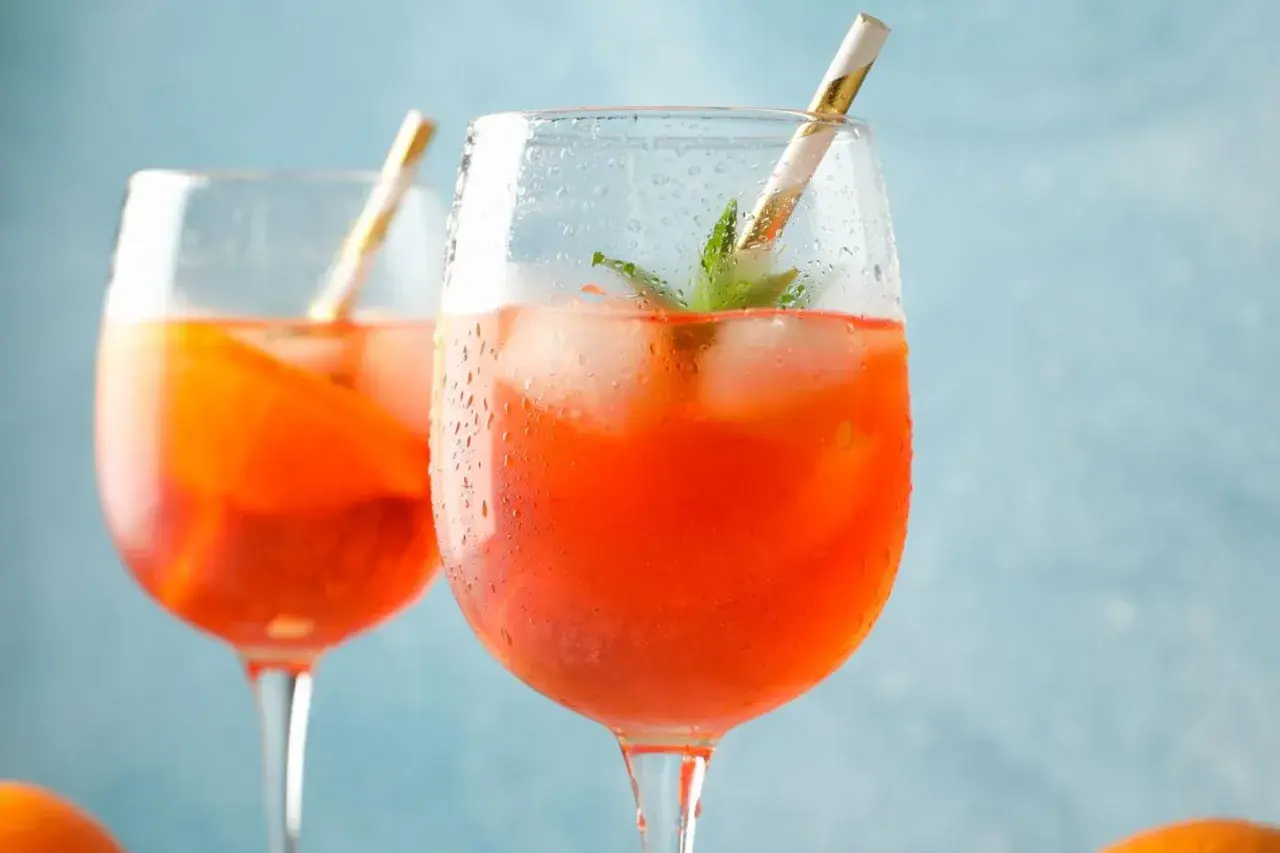 Zwei erfrischende Aperol Spritz mit Eis und Minze, bereit für einen sonnigen Nachmittag.