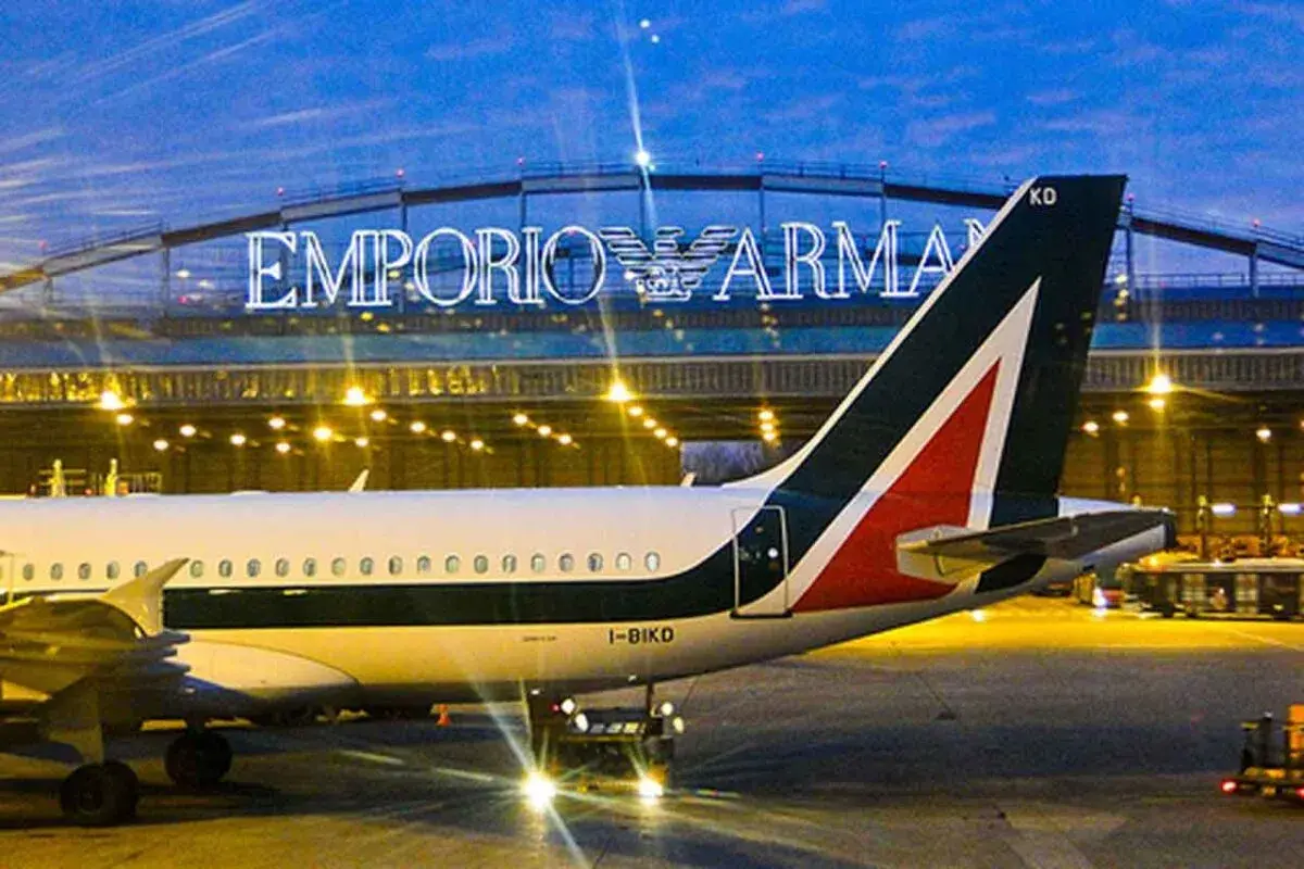 Samolot Alitalia na lotnisku w Mediolanie, w tle podświetlony napis Emporio Armani.