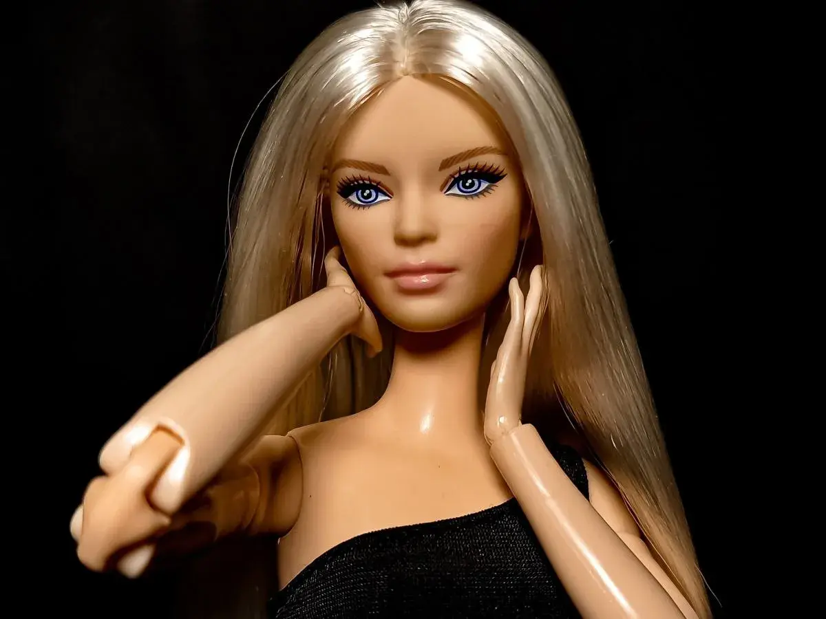Lalka Barbie z blond włosami i niebieskimi oczami, w czarnej sukience, symbolizuje emancypację kobiet.