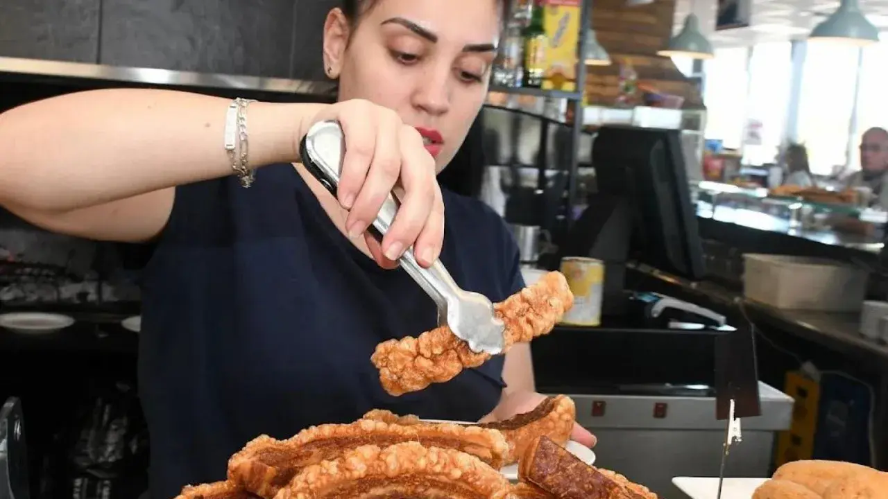 Camarera sirviendo crujiente chicharrón, perfecto para comer en carretera cerca de Zaragoza.