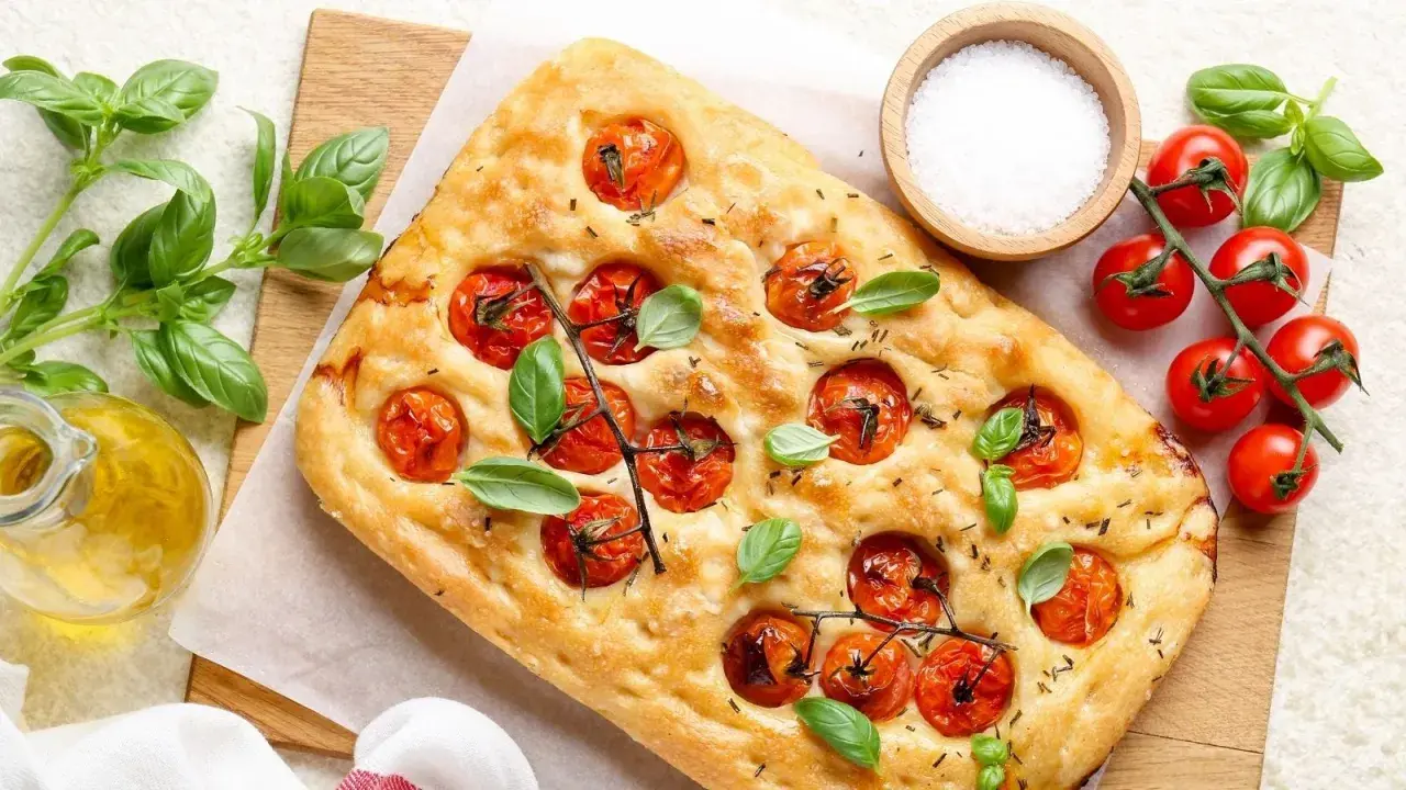 Pyszna focaccia z pomidorkami koktajlowymi i bazylią, idealna do pesto.