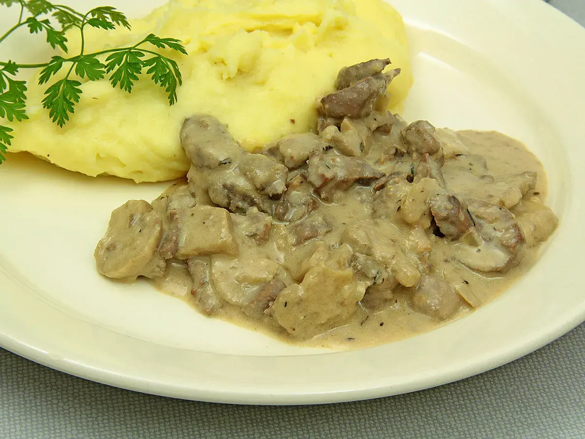 Rognons de porc en sauce crémeuse avec des champignons, servis avec une purée de pommes de terre onctueuse. Parfait pour savoir avec quoi accompagner des rognons de porc.