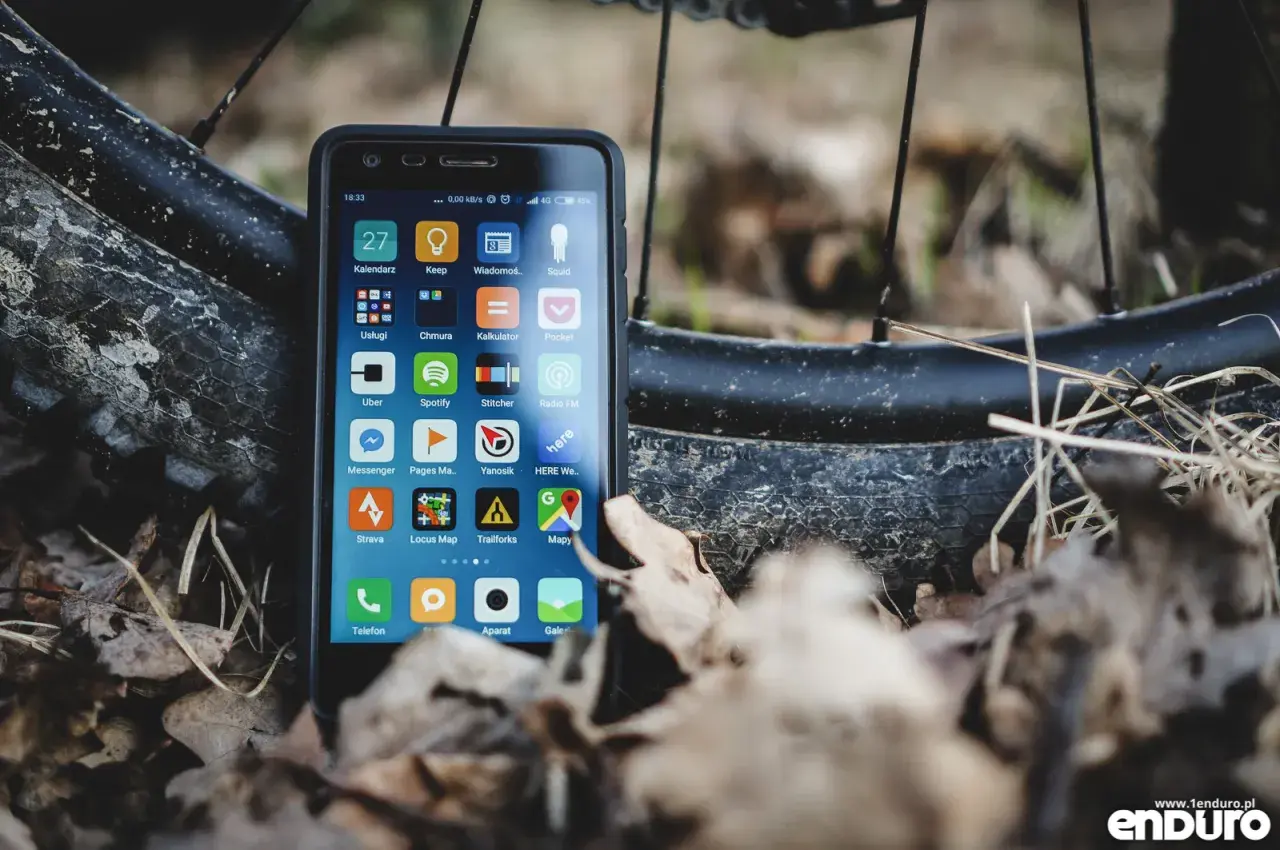 Szukasz alternatywy dla Endomondo za darmo? Smartfon z aplikacjami do śledzenia aktywności, jak Strava czy Locus Map, leży obok opony rowerowej.