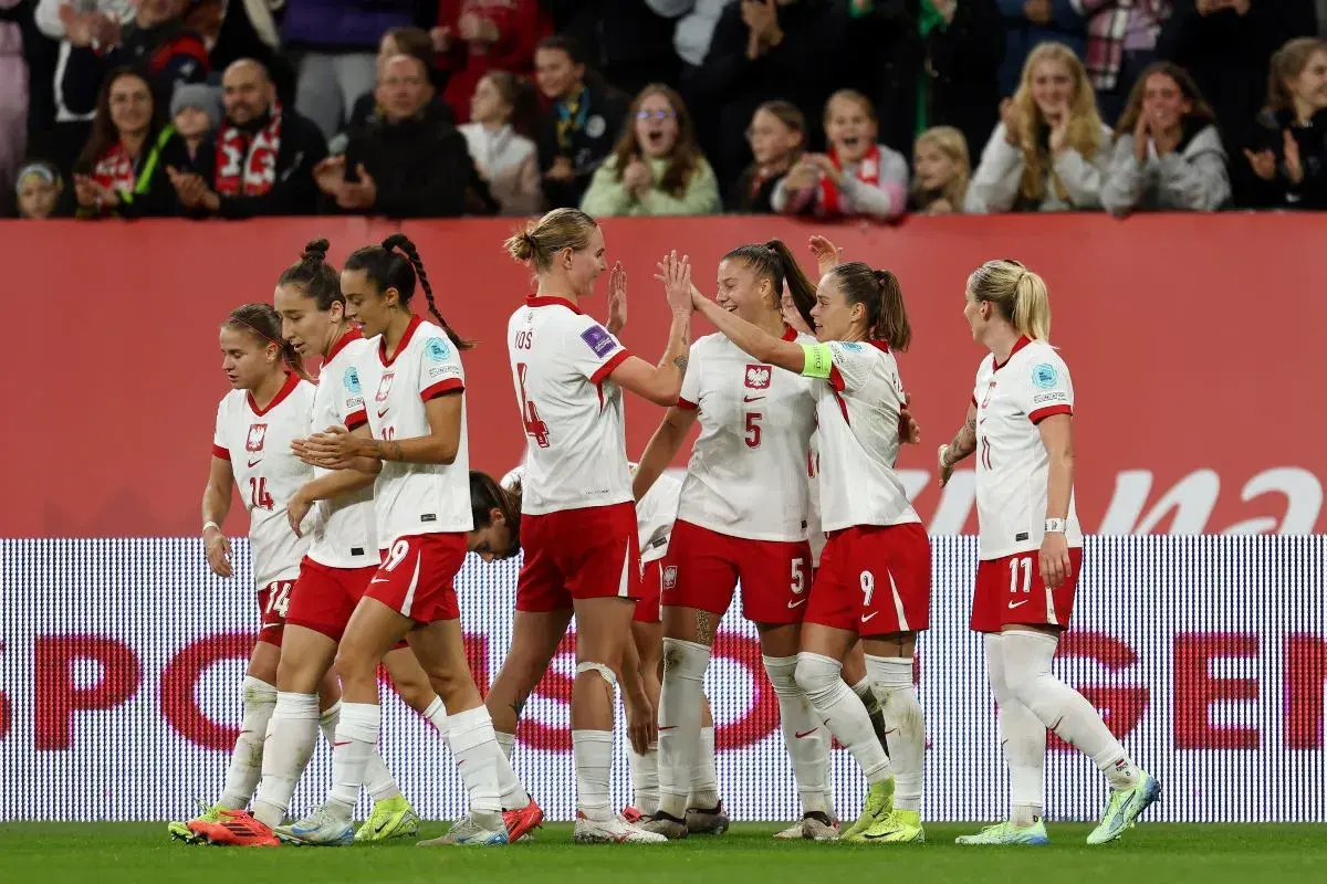 Piłkarki w biało-czerwonych strojach świętują sukces. To dumne polskie dania na boisku, pełne radości i sportowego ducha.