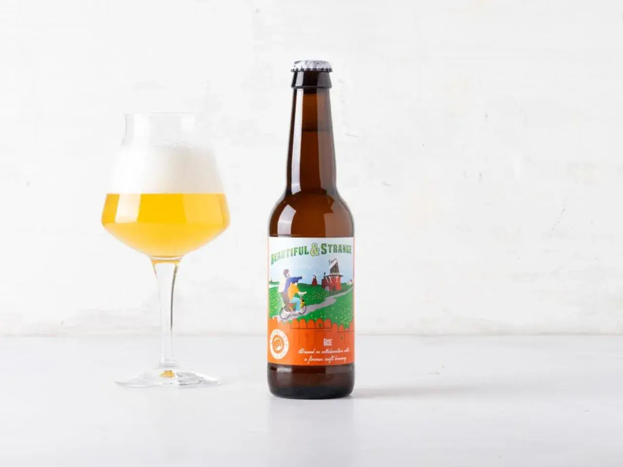 Bicchiere di birra dorata con schiuma bianca accanto a una bottiglia di birra "Beautiful & Strange" Gose, una birra salata dal gusto unico.