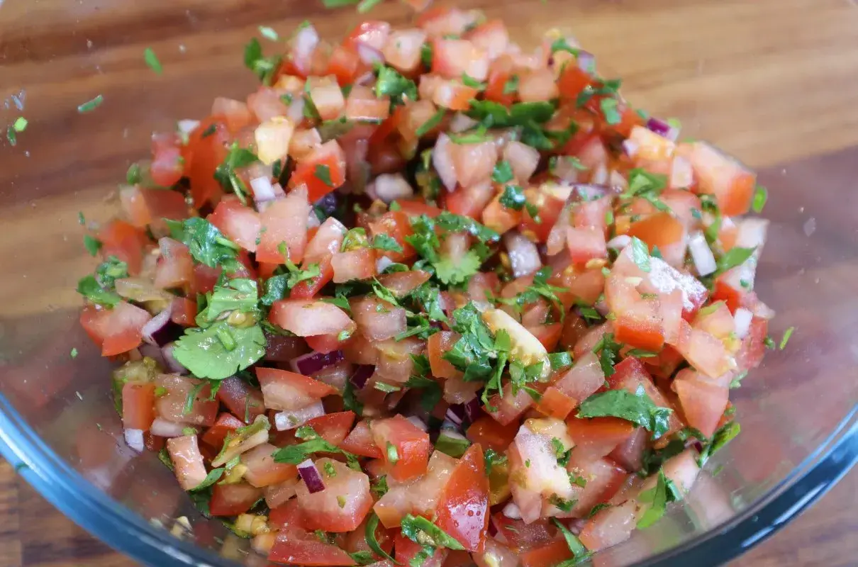 Świeża, kolorowa salsa z pomidorów, cebuli i kolendry w szklanej misce. Idealna do nachos lub jako dodatek do dań.