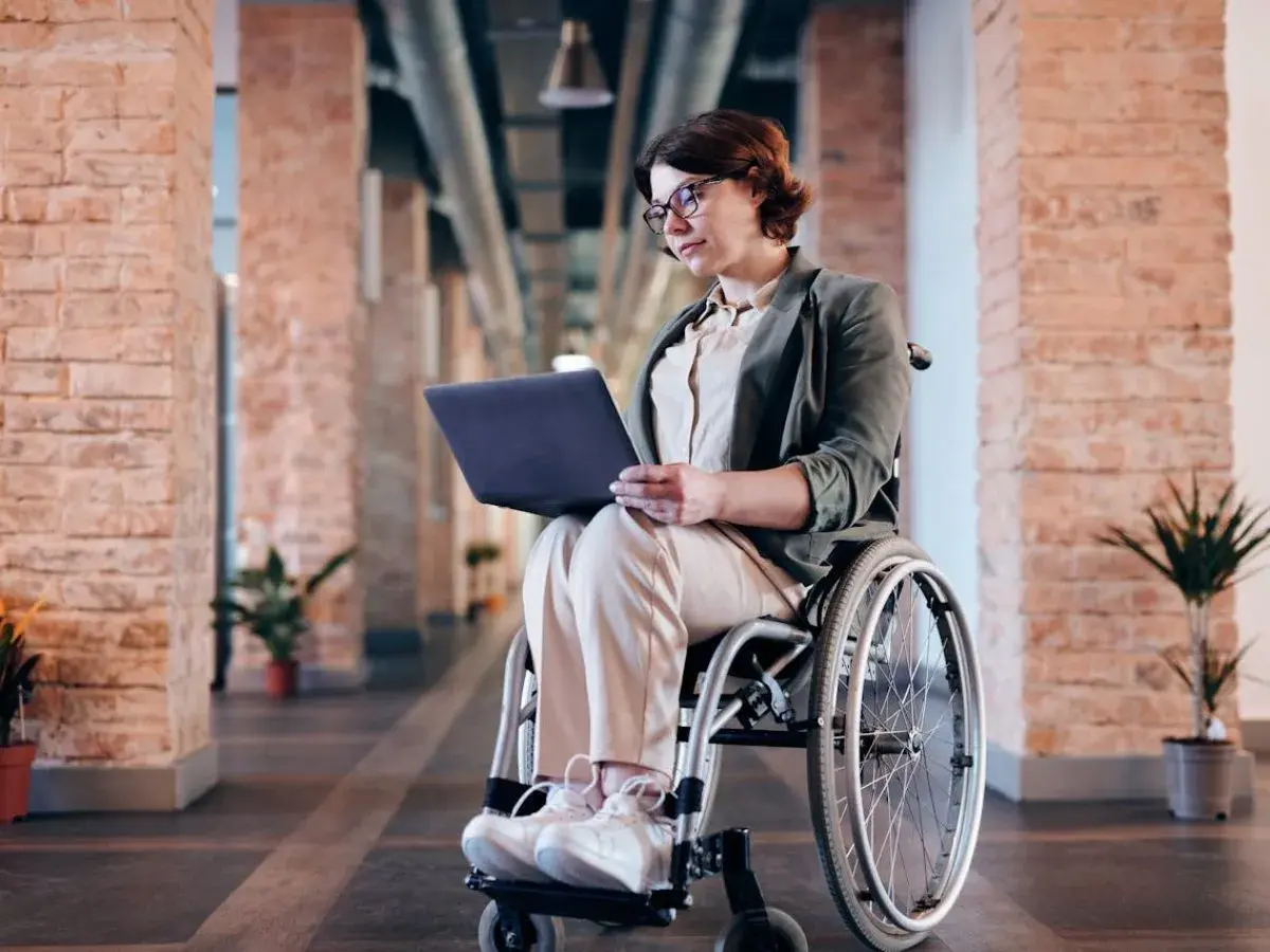 Kobieta na wózku inwalidzkim pracuje na laptopie. Czy lekarz rodzinny może wystawić zlecenie na wózek inwalidzki?