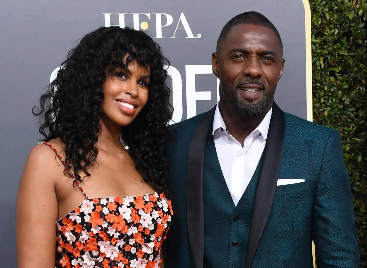 Idris Elba z żoną, Sabriną Dhowre, na czerwonym dywanie. Ona w kwiecistej sukience, on w eleganckim garniturze.
