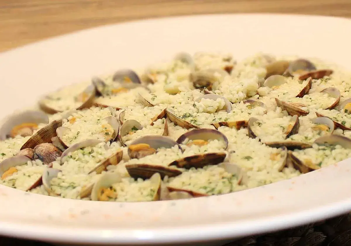 Delicioso arroz con almejas, un plato de marisco cremoso y lleno de sabor, adornado con perejil fresco.