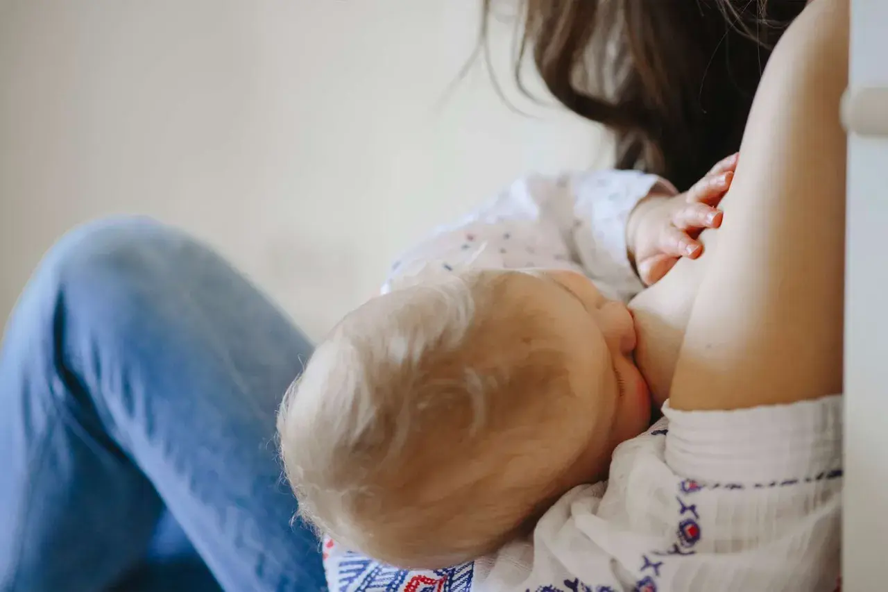 Mamma allatta il suo bambino, dimostrando che si può allattare con la febbre. Un momento di amore e cura.