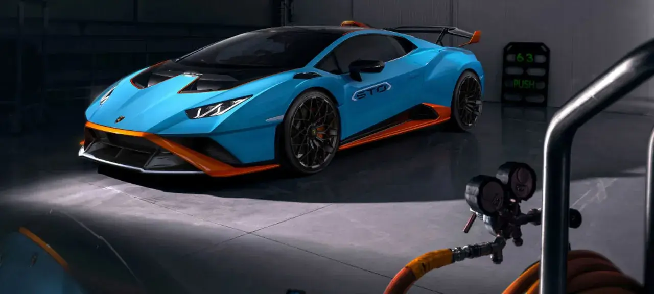 Niebieskie Lamborghini Huracán STO z pomarańczowymi akcentami w garażu.