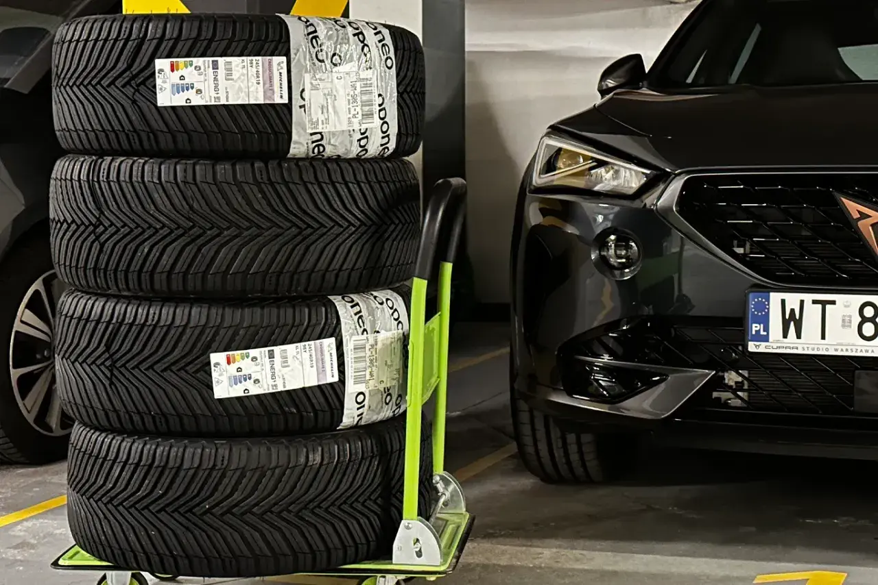 Cztery nowe opony Michelin CrossClimate 2, uznawane za najlepsze opony wielosezonowe, czekają na montaż w czarnym aucie.