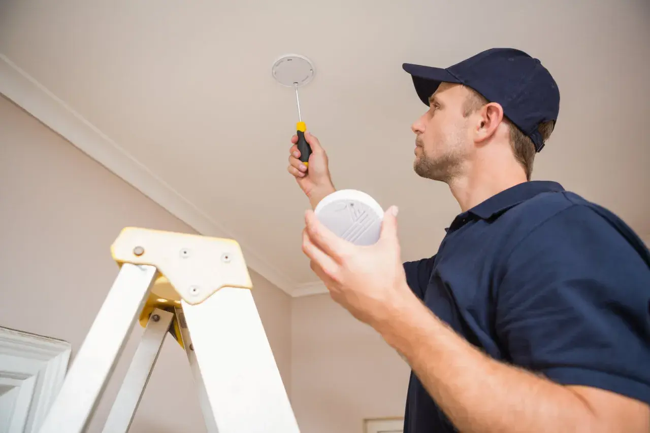 Un technicien installe des alarmes incendie au plafond, assurant la sécurité de votre domicile.