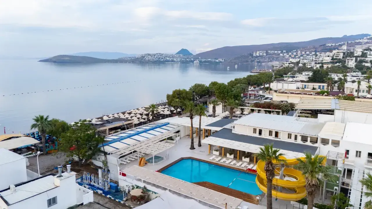 Widok na basen i plażę z leżakami. W tle morze i zabudowania. Idealne miejsce na wakacje, jak sugerują petunya beach resort opinie.