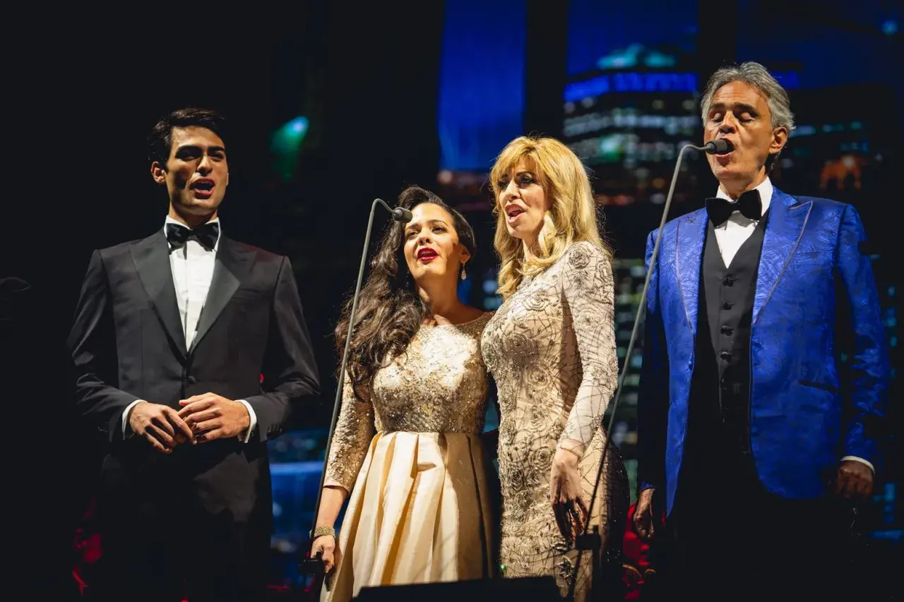 Andrea Bocelli śpiewa z synem i dwiema artystkami na scenie.