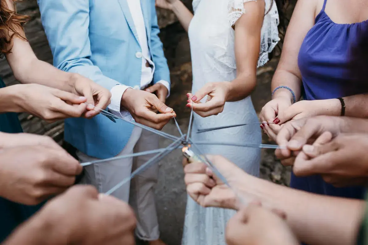 Manos sostienen bengalas formando un círculo, creando un ambiente festivo para juegos para bodas.