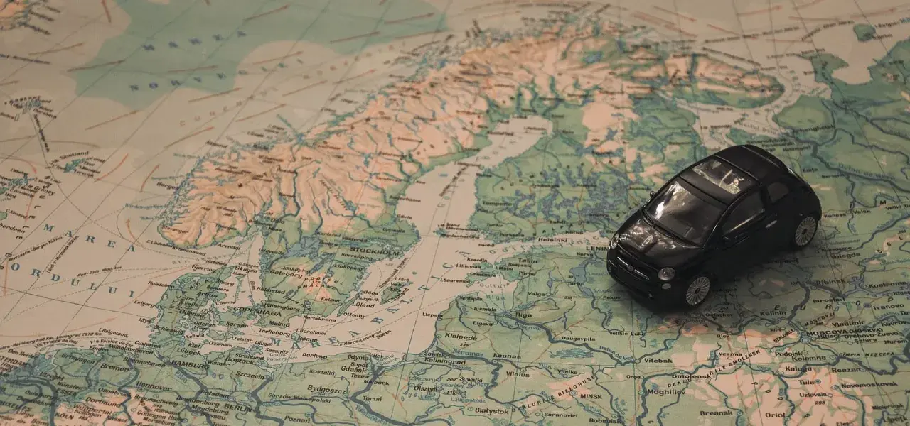 Czarny Fiat 500 na mapie Europy, planujący podróż na Mikołajki do Olsztyna.