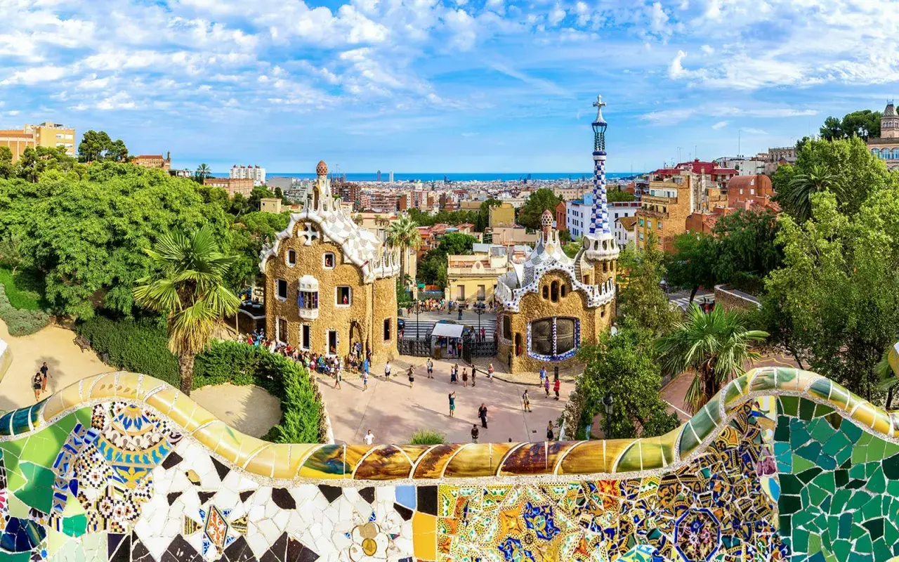 Kolorowa mozaika wita podczas zwiedzania Parku Güell. W tle bajkowe domki i panorama Barcelony.