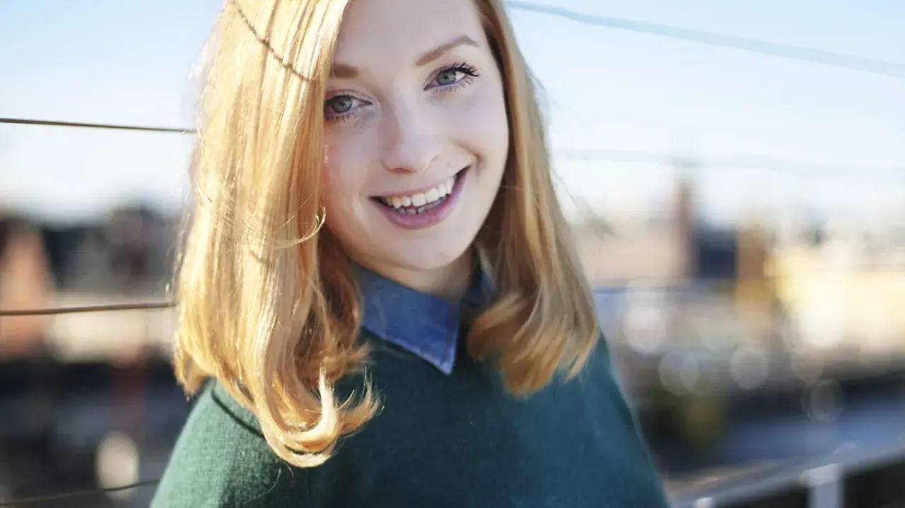 Glad ung kvinna med blont hår ler mot kameran. Hennes sandra beijer ålder är svår att avgöra, men hon utstrålar ungdomlig energi.