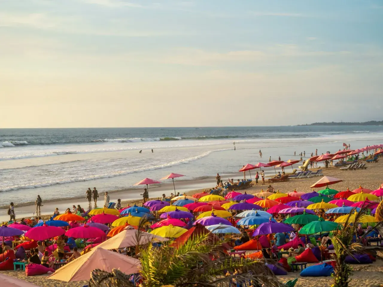 Kolorowa plaża na Bali, pełna parasoli i ludzi relaksujących się na leżakach. Idealne miejsce na wakacje.