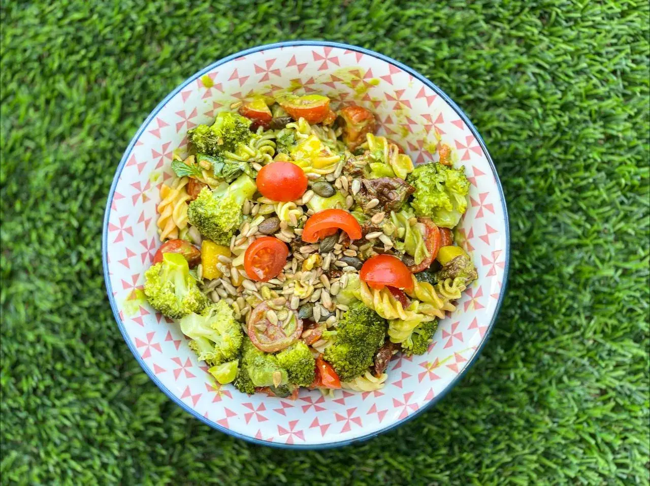 Ensalada de pasta con brócoli, tomates cherry y semillas. Los ingredientes frescos y coloridos la hacen irresistible.