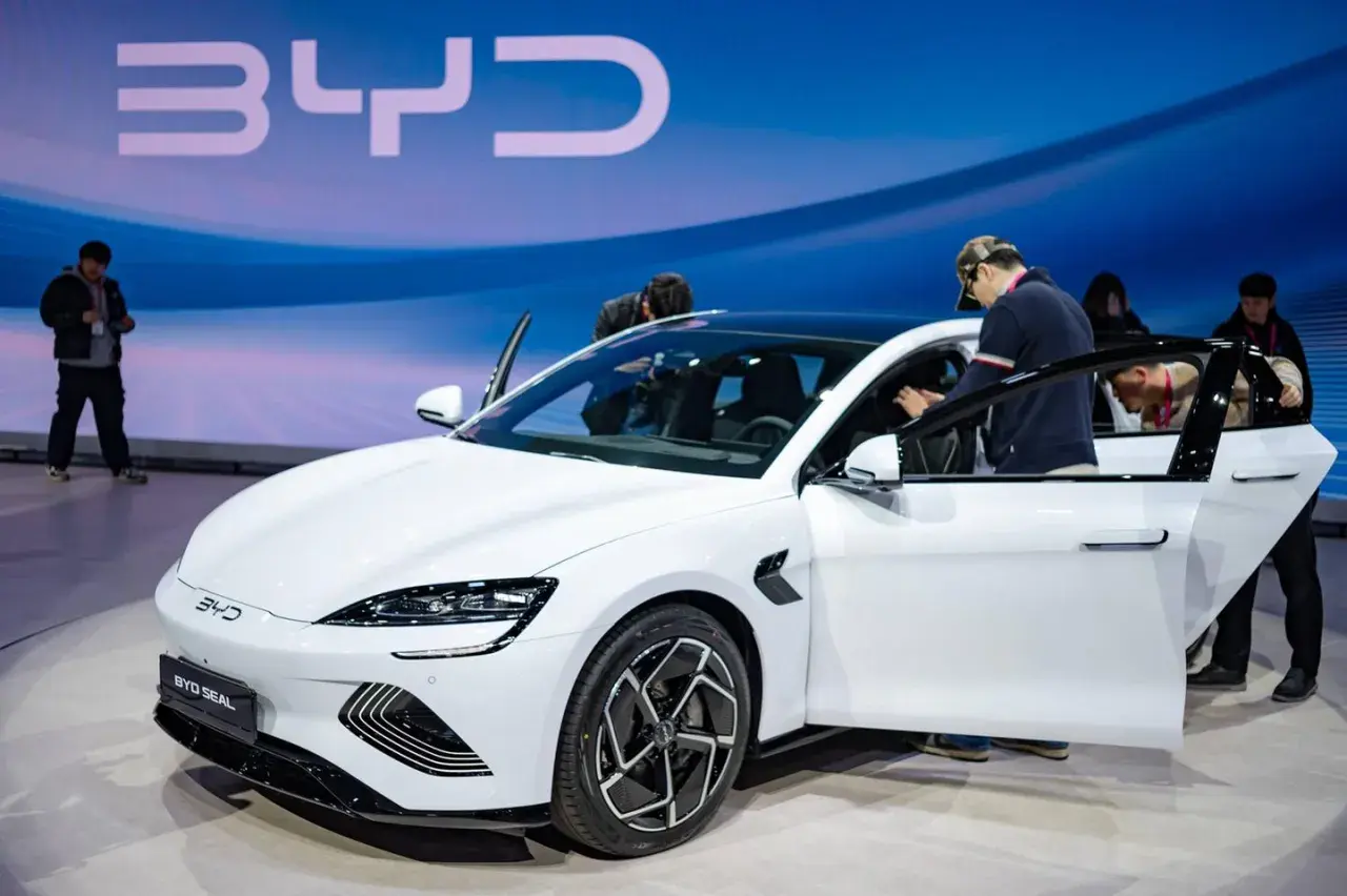 Weißer BYD Seal auf einer Messe, Leute steigen ein. Die BYD Aktien könnten bald steigen.