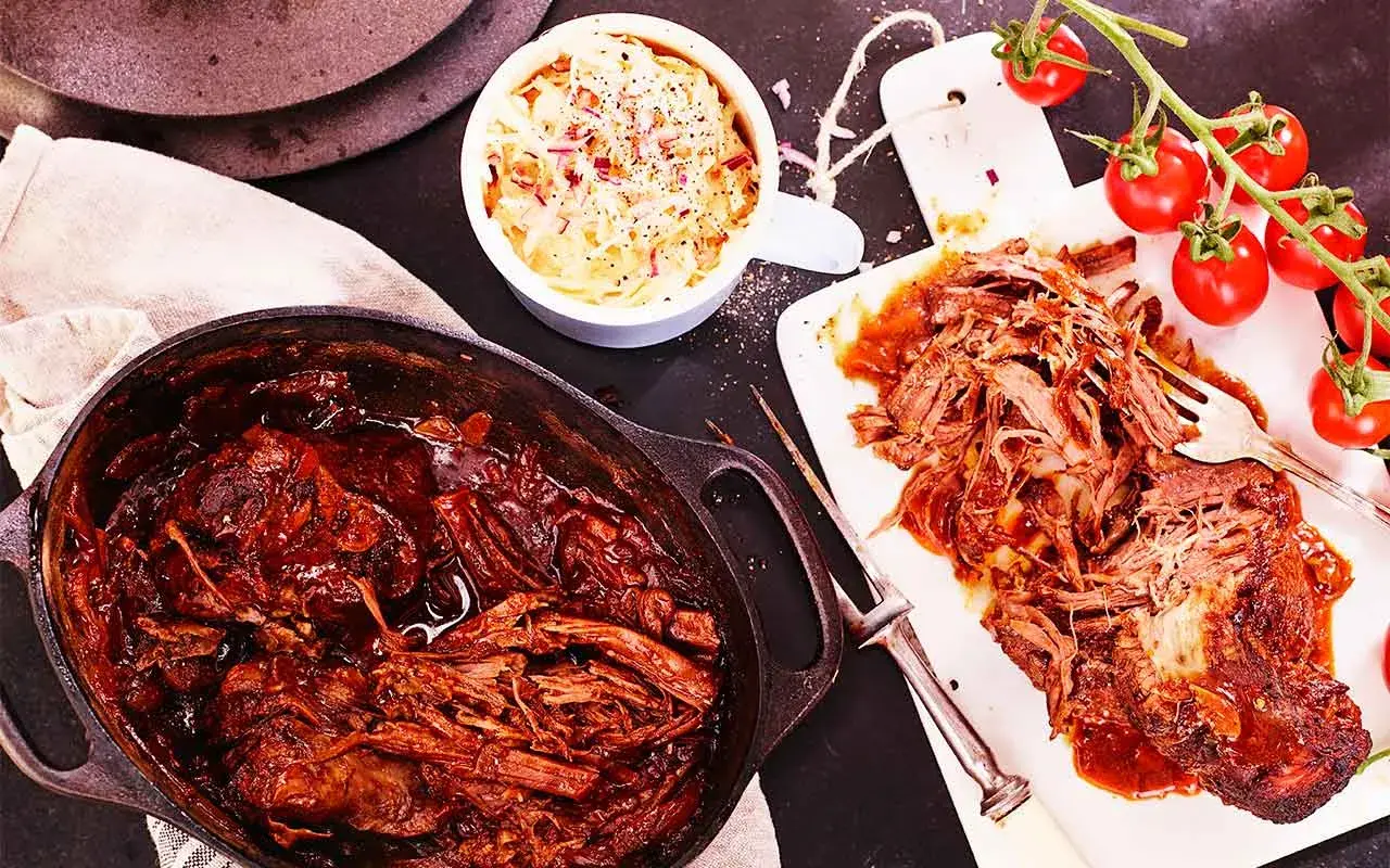 Saftigt pulled beef i en gjutjärnsgryta, serverat med krämig coleslaw och färska tomater. Perfekt för en mysig middag.