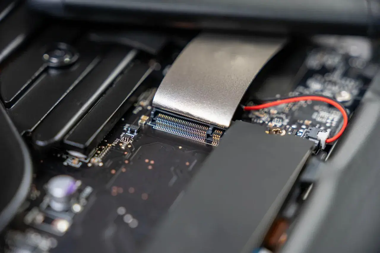 Nahaufnahme eines Motherboards, bereit für die m2 ssd installieren. Ein silbernes Kabel ist mit einem Anschluss verbunden.