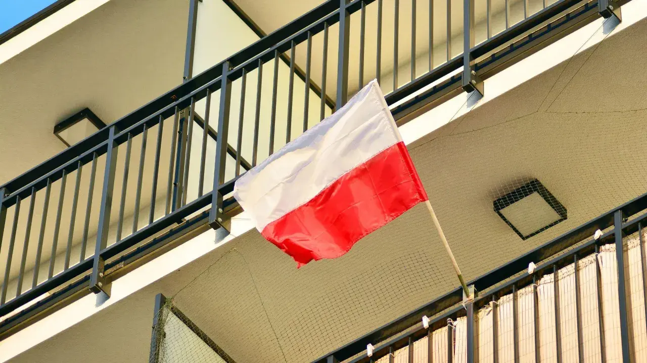 Polska flaga powiewa na balkonie. Biało-czerwone barwy symbolizują dumę i historię narodu.