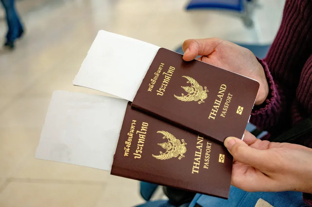 Zwei Reisepässe von Thailand werden gehalten, bereit für die Einreise. Ein 10-Jahres-Visum Thailand ist vielleicht schon beantragt.