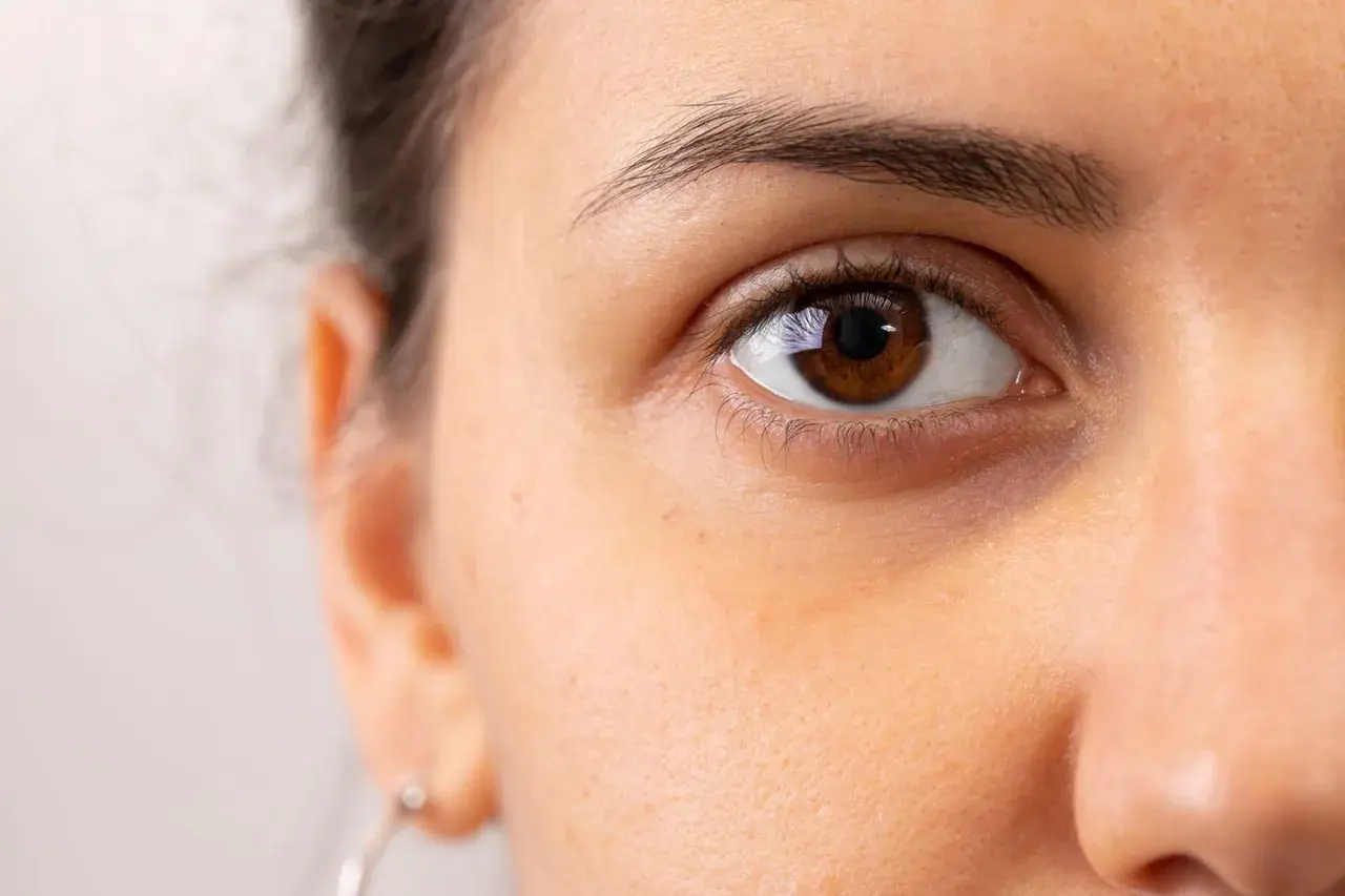 Nahaufnahme eines braunen Auges mit sichtbaren Schatten, die dunkel zwischen Nase und Auge liegen.