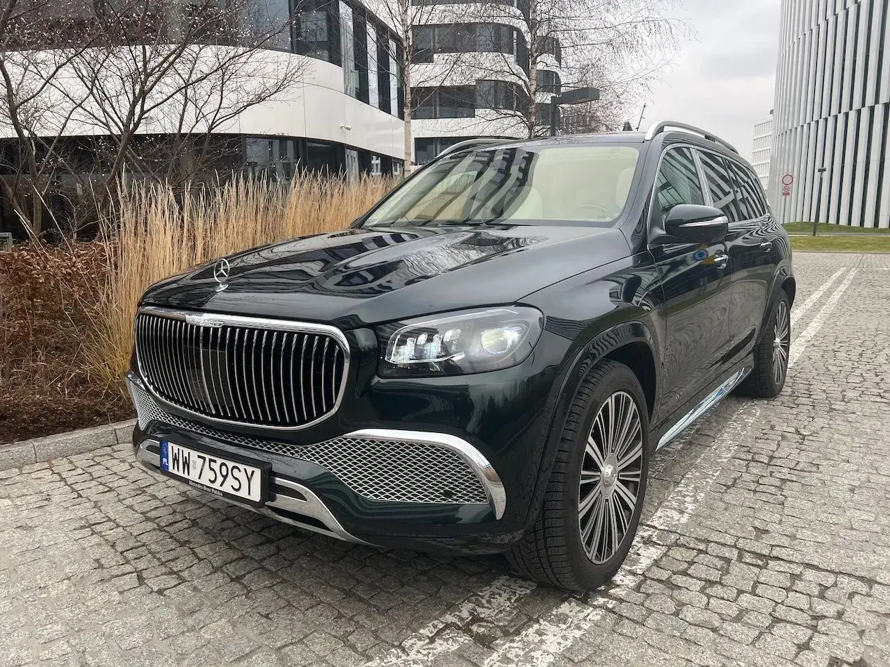Elegancki, czarny GLS Maybach lśni na tle nowoczesnej architektury.