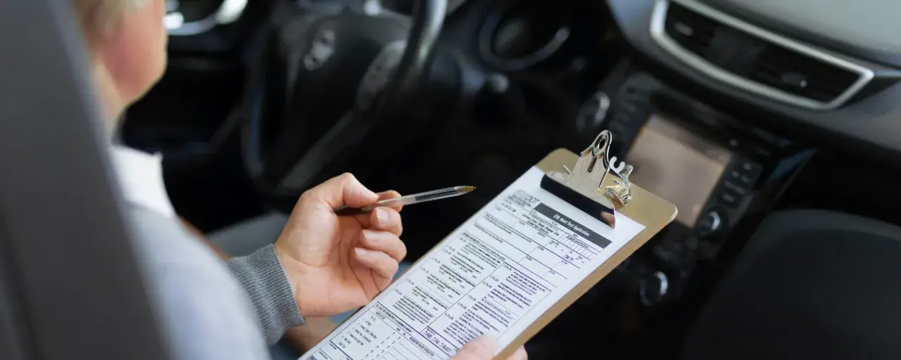 Persona revisa un formulario de solicitud de examen de manejo, preparándose para obtener su carnet coche automático.
