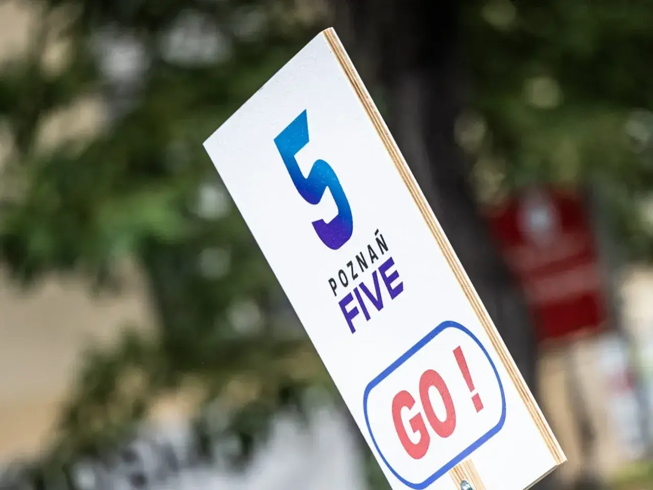 Tabliczka z napisem "POZNAŃ FIVE GO!" zachęca do startu w biegu na 5 kilometrów.
