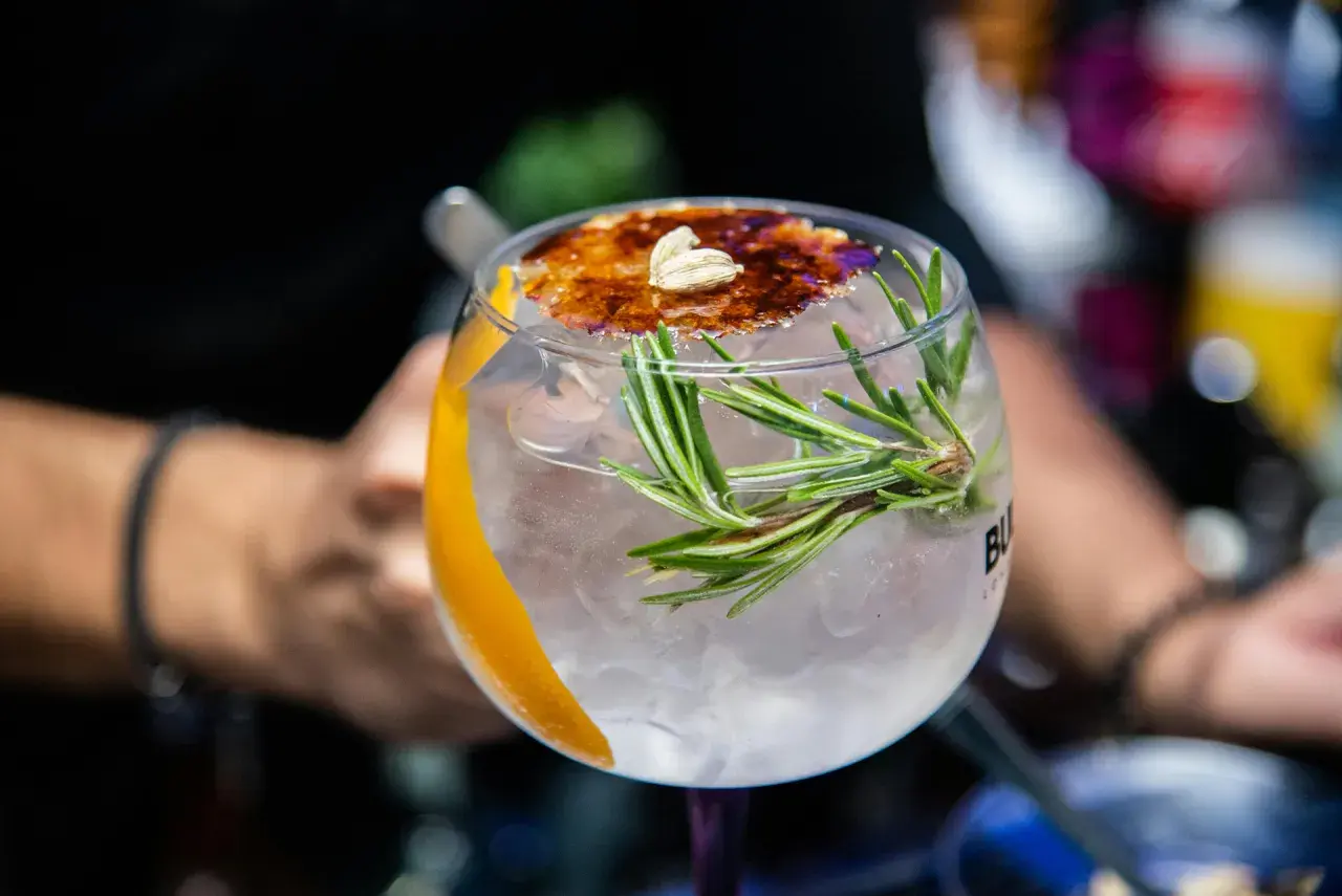 Ein erfrischender Gin Tonic mit Rosmarin und karamellisierter Orangenscheibe, einer der besten Gin Cocktails.