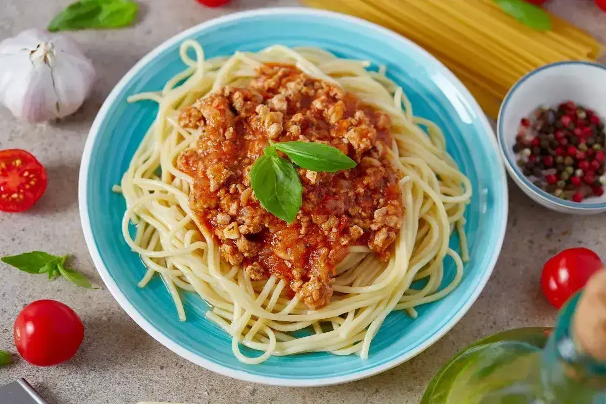 Spaghetti bolognese na talerzu, ozdobione bazylią. Idealne na prosty przepis obiadowy.