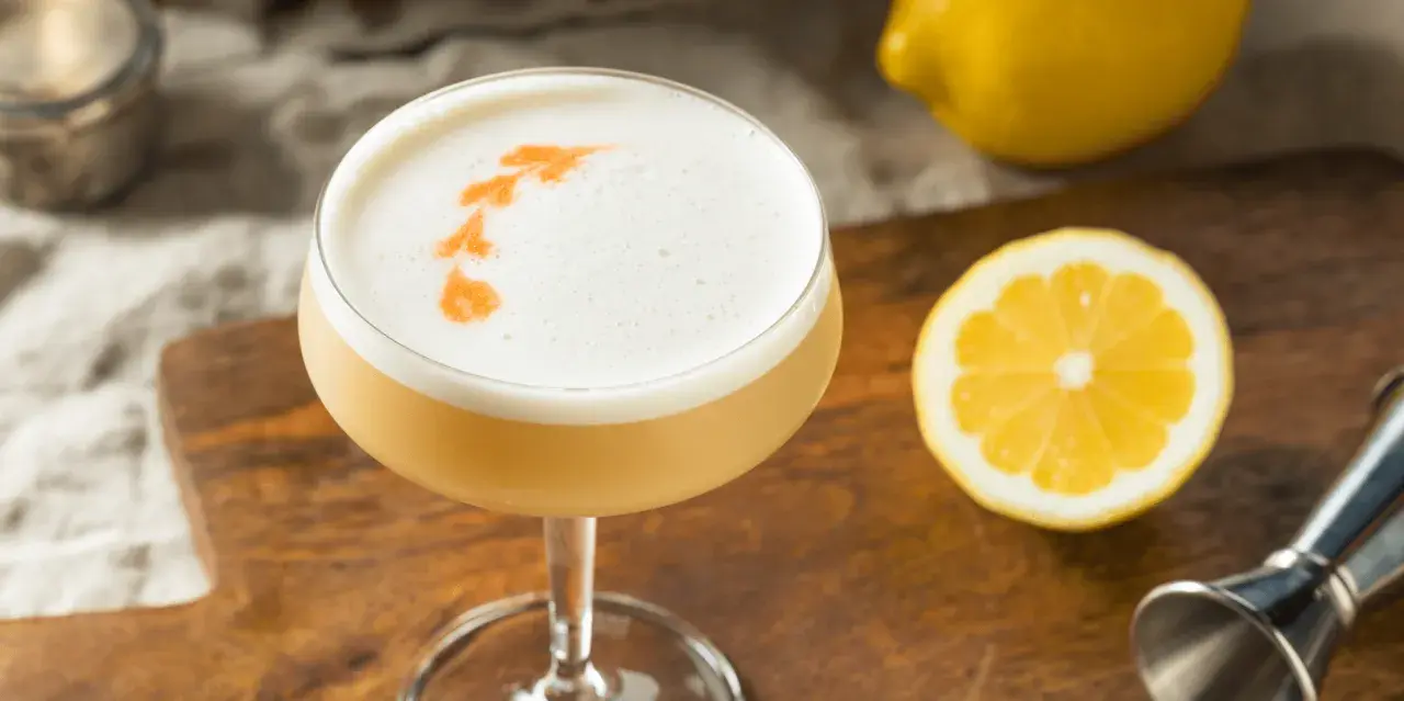 En drink med fluffigt kokosskum och en citronskiva bredvid.