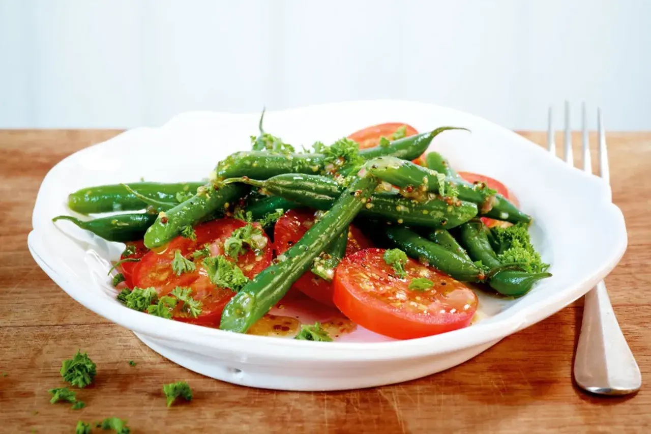 Frischer Bohnen Tomaten Salat mit Kräutern und einer leichten Vinaigrette, serviert auf einem weißen Teller.