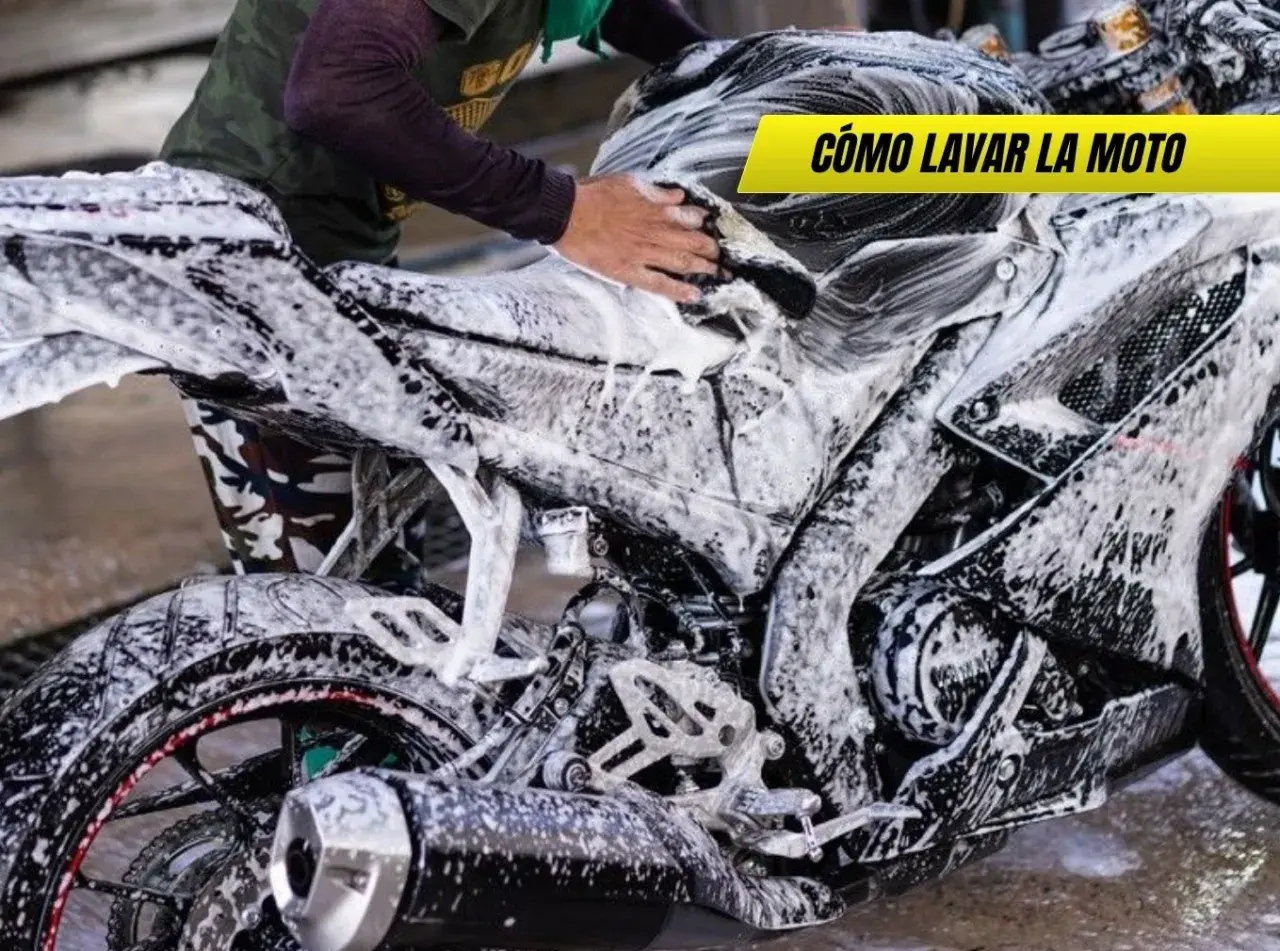 Persona lavando una moto deportiva con espuma. Se ve el motor, la rueda trasera y el tubo de escape. ¡Así se limpia la moto!