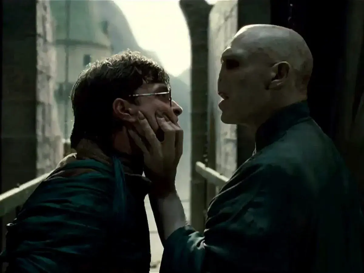 Ralph Fiennes jako Voldemort grozi Harry'emu Potterowi, chwytając go za twarz.