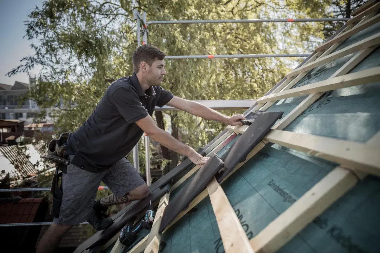 Handwerker verlegt Dachziegel, um die Dachkehle abzudichten.