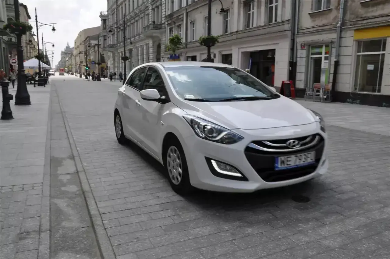 Biały Hyundai i30 1.4 benzyna na brukowanej ulicy w mieście.