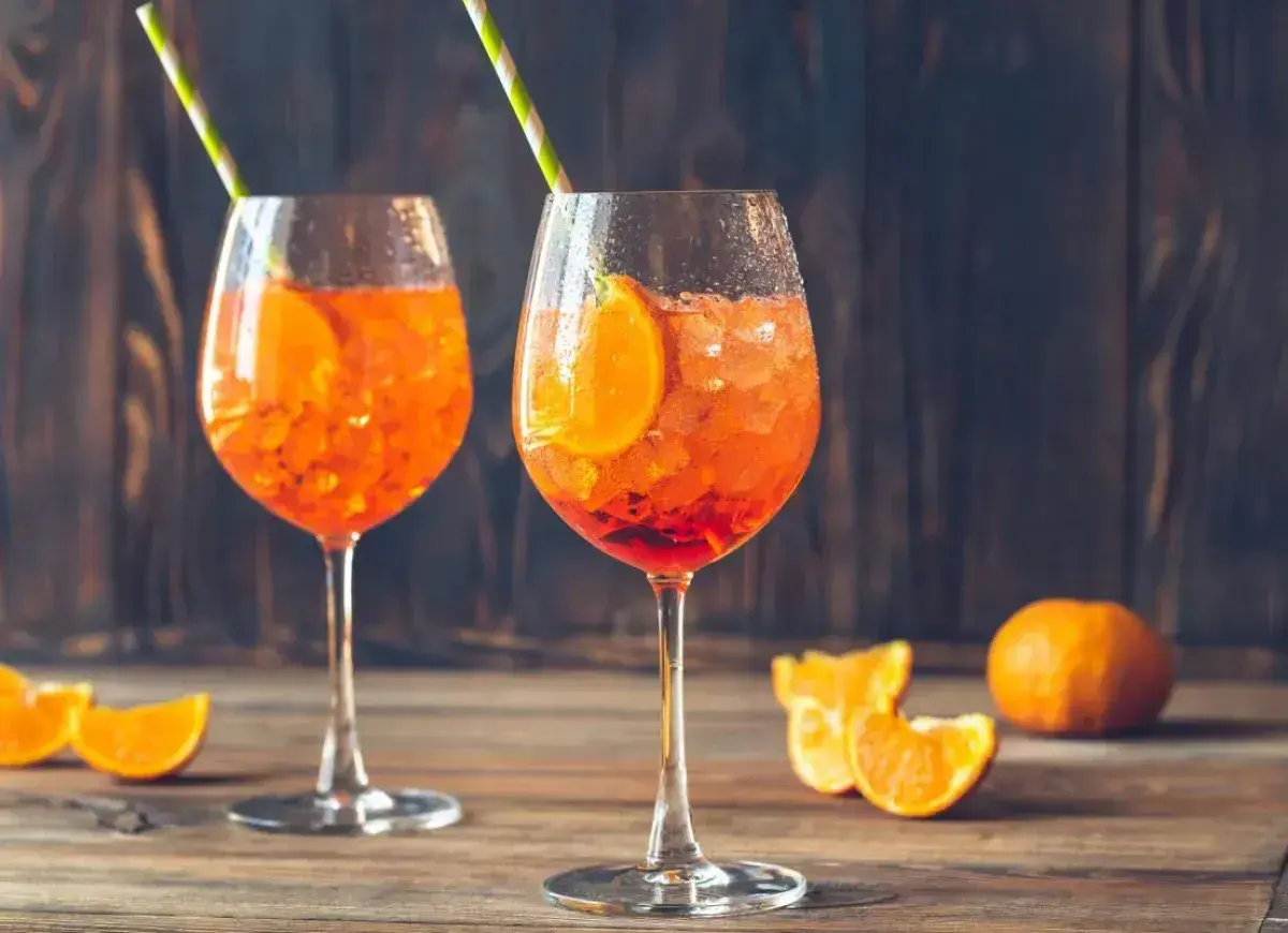 Dwa orzeźwiające Aperol Spritz z plasterkami pomarańczy i słomkami. Idealne na lato, a ich aperol spritz kcal nie są wysokie.
