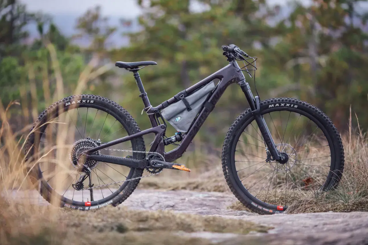A dark purple Santa Cruz Tallboy 4 mountain bike rests on rocky terrain, ready for an adventure.