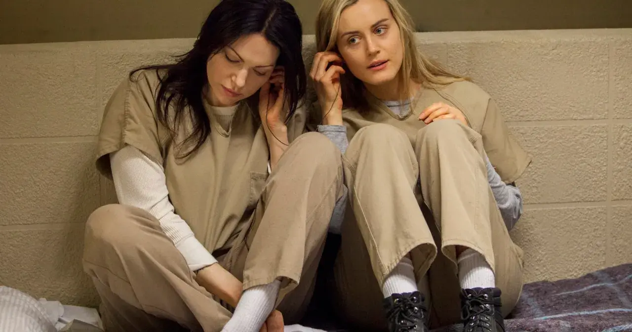 Dwie kobiety w więziennych strojach słuchają muzyki. To scena z serialu "Orange Is the New Black", popularnego filmu o lesbijkach na Netflix.