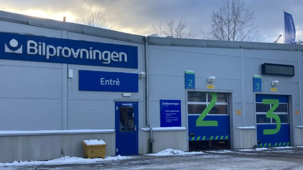Bilprovningen med entré och garageportar för besiktning. En varningstriangel syns inte, men bilen är redo för kontroll.