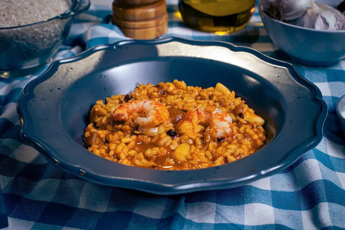 Un plato de paella mixta con gambas y arroz dorado, listo para disfrutar.