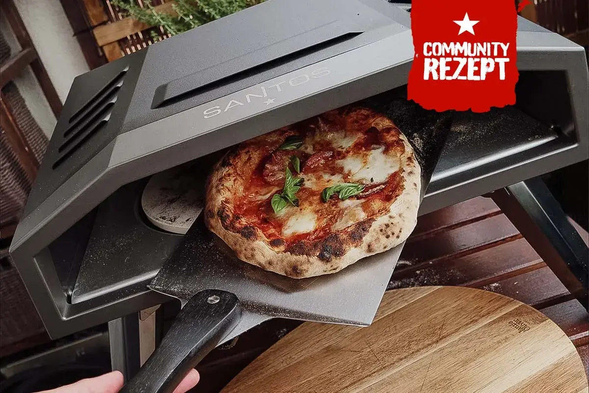Eine frisch gebackene Pizza wird aus einem Santos Pizzaofen auf eine Pizzaschaufel gehoben.