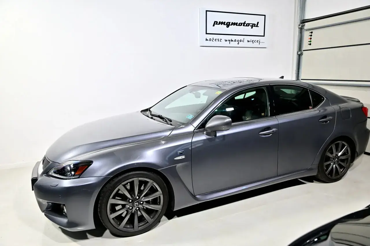 Szary Lexus IS F w garażu, z logo "pmgmotopl" na ścianie.
